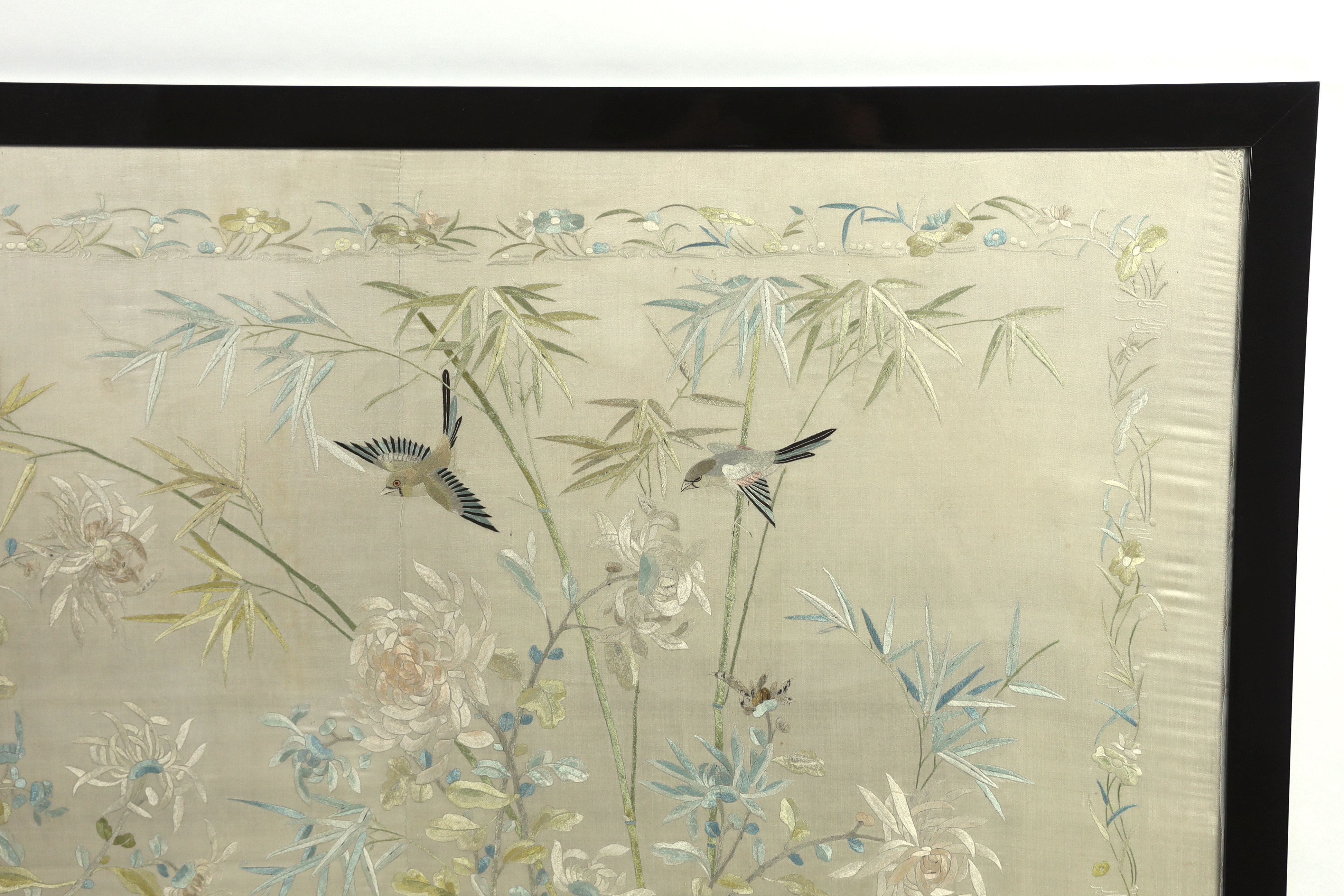 A framed early 20th century Chinese silk embroidered shawl, embroidered with chickens, ducks, flying birds and insects amongst bamboo and flowering plants, 126cm wide x 10.5cm high